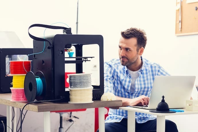 Homem trabalhando em uma impressora 3D aberta
