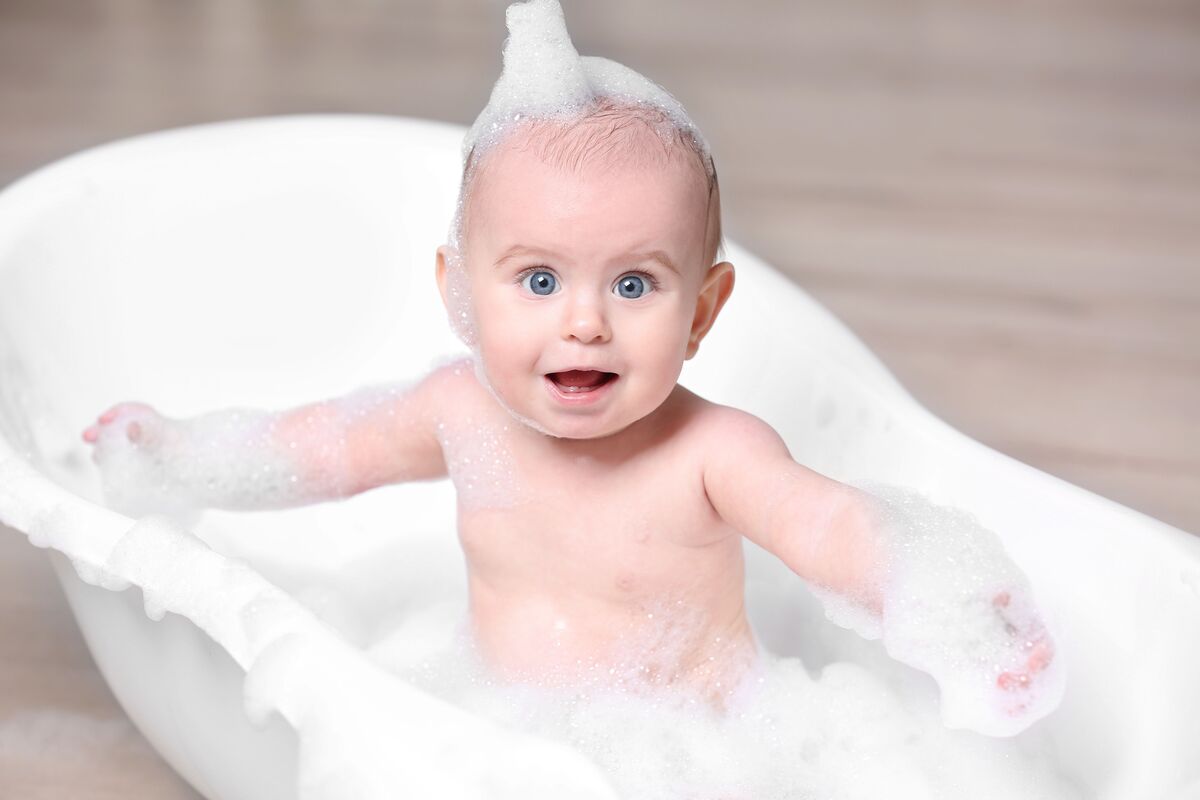 Bebê em banheira com espuma no corpo