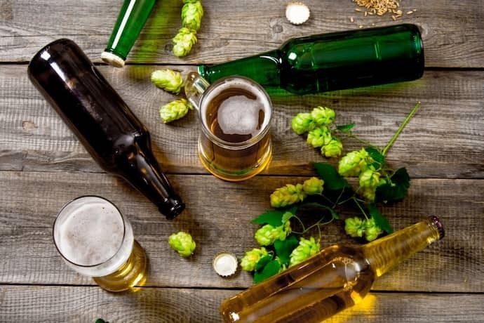 Cerveja, malte e lúpulo verde em uma mesa de madeira