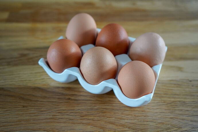 Porta ovos de plástico em mesa de madeira. 