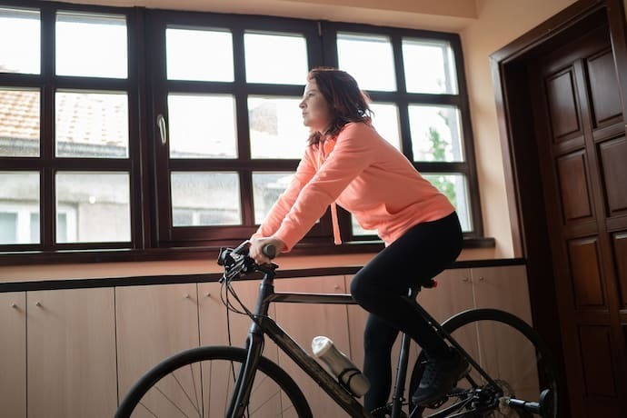 Mulher treinando para ciclismo em casa.