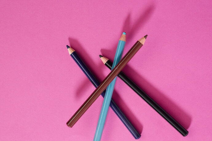 Delineadores coloridos em lápis em fundo rosa
