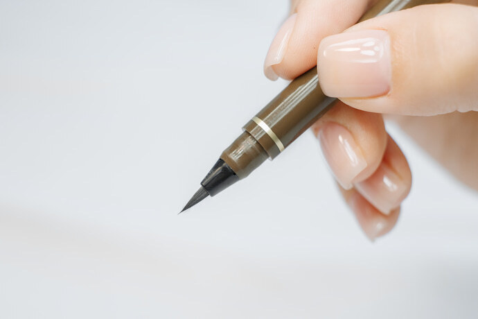 Mulher usando caneta para sobrancelha marrom