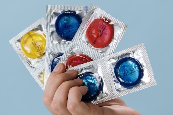Mão segurando vários pacotes de preservativo