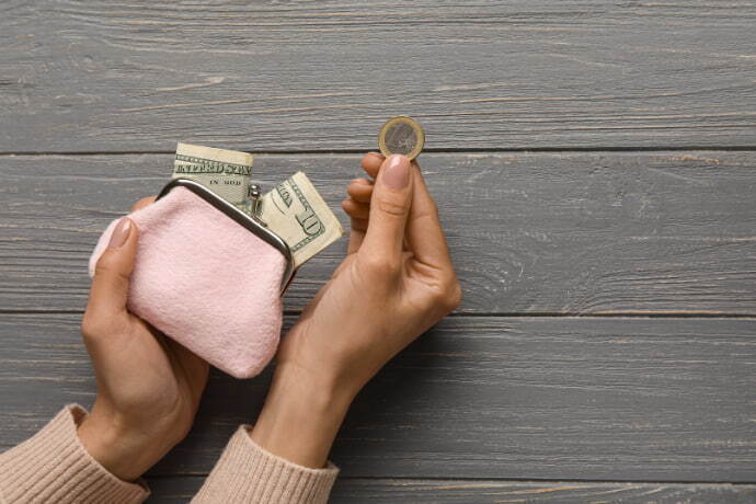 Mulher segurando a carteira rosa com dinheiro
