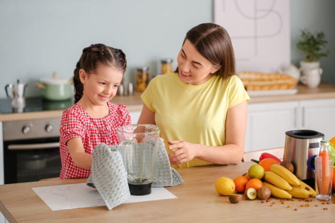 Mãe e filha secando com pano o liquidificador na cozinha