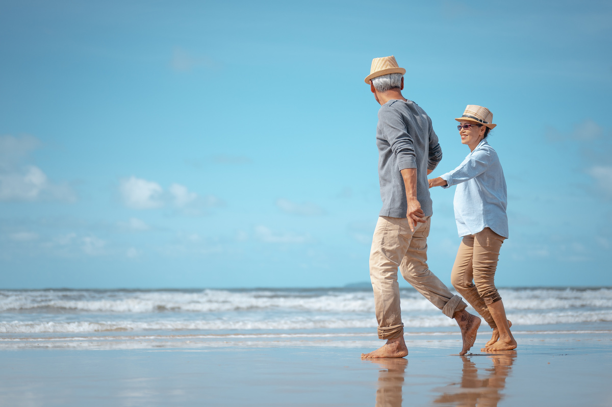 Um casal de idosos andando na praia