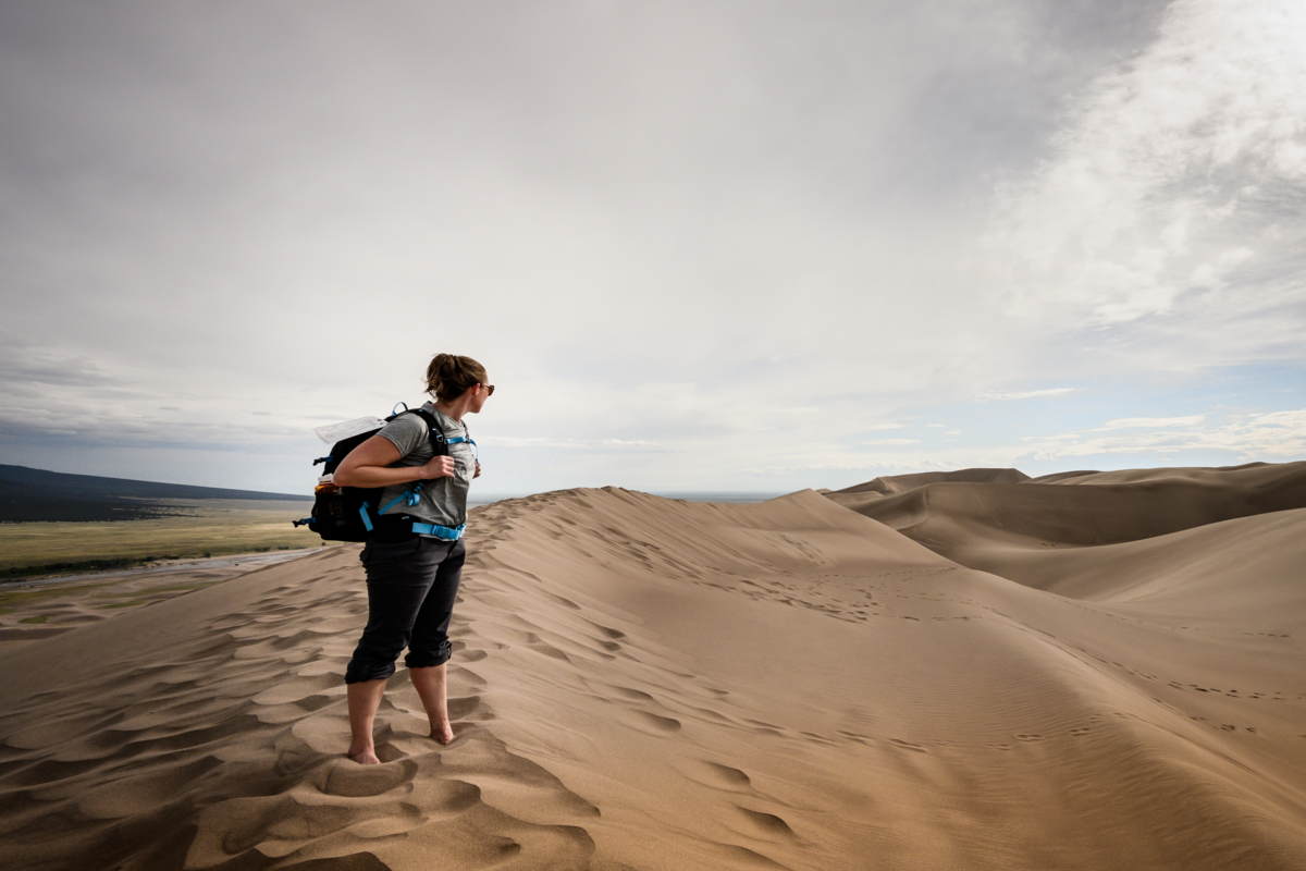 Mulher caminhante olha para trás na crista das dunas