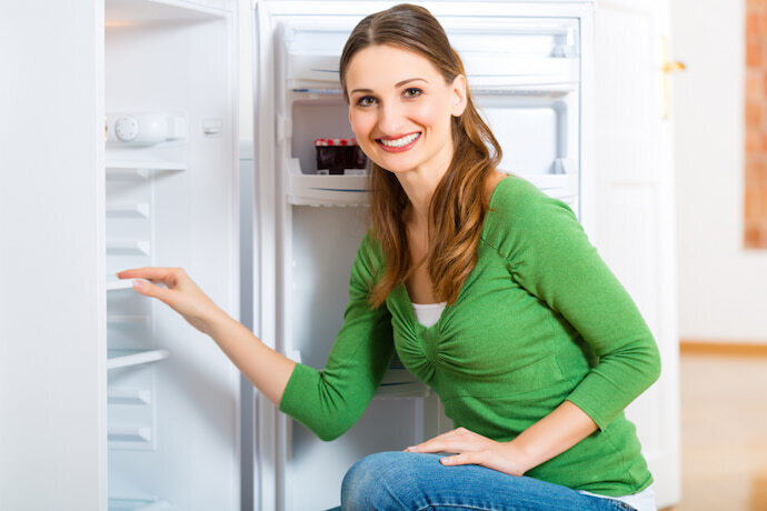 Mulher sorridente verificando a parte interna da geladeira.