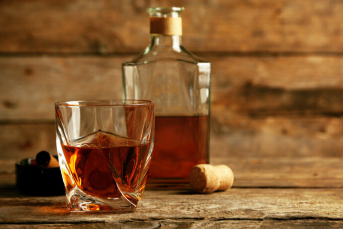 Copo e garrafa de whisky sobre uma mesa de madeira