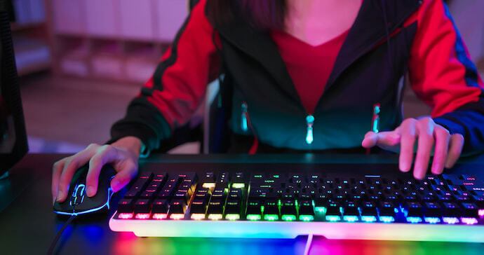 Gamer sentado e utilizando um teclado.
