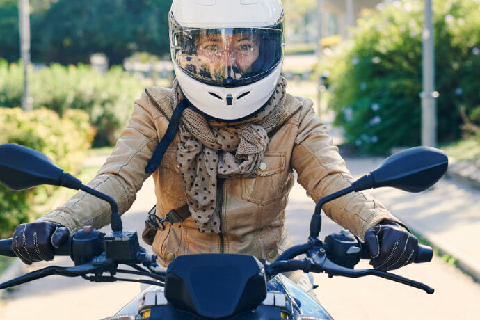 Mulher com capacete pilotando uma moto