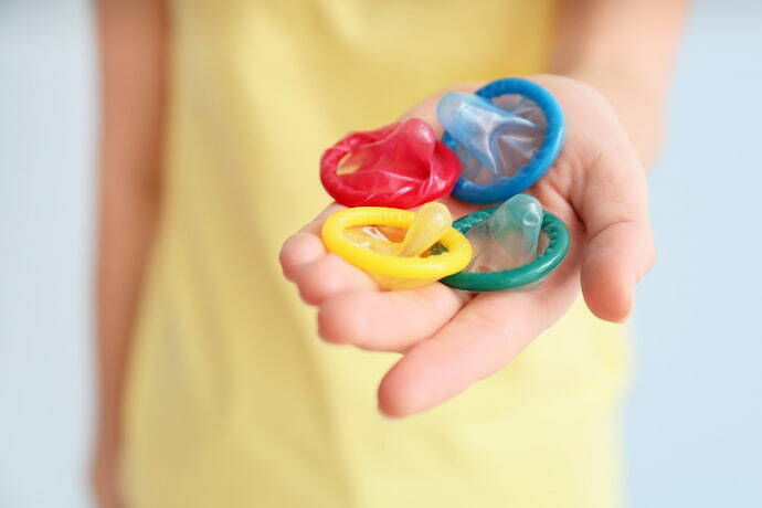 Mulher segurando preservativos coloridos 