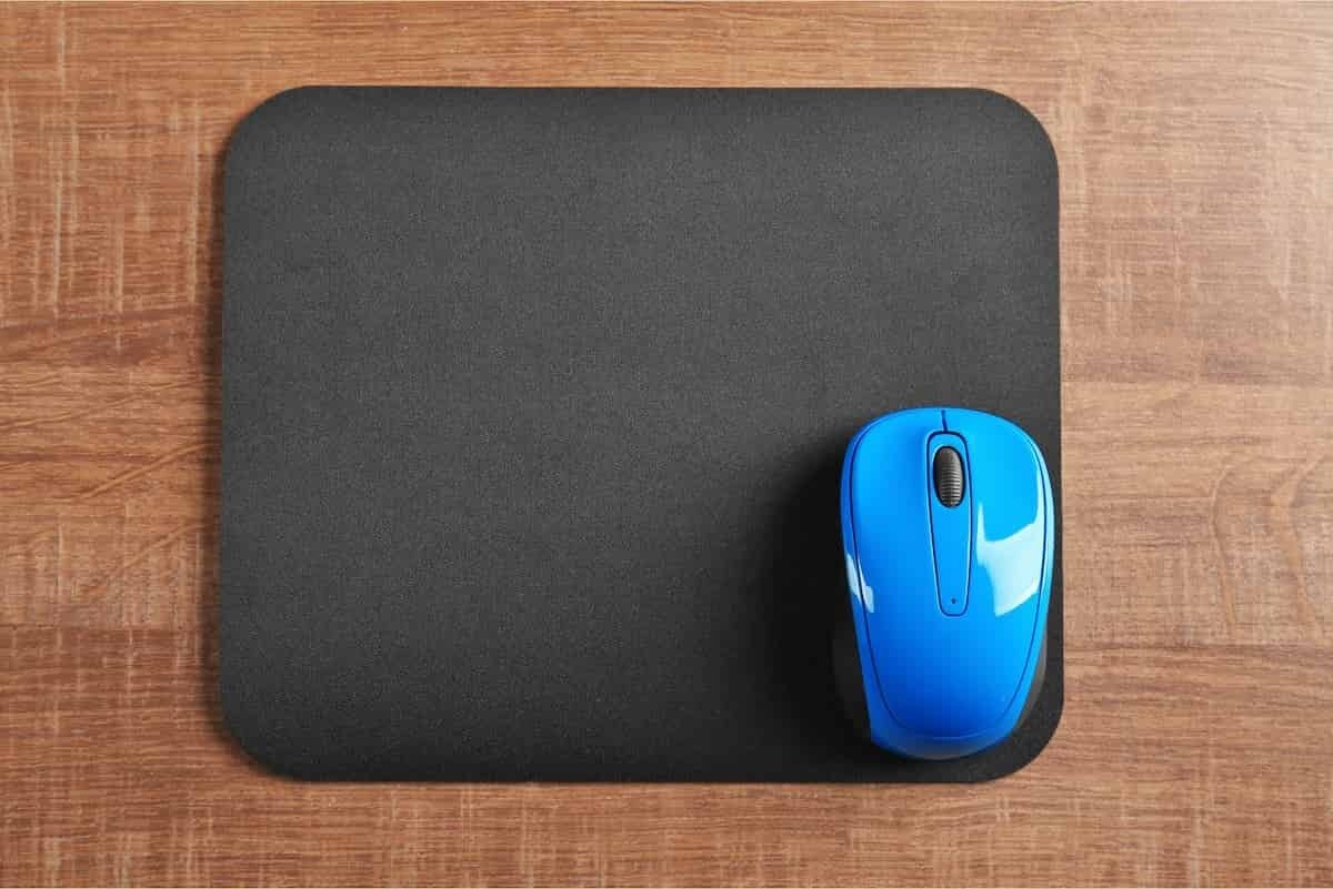 Mousepad preto sobre superfície de madeira 