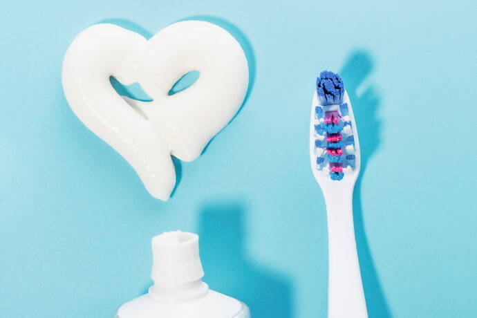 Pasta de dentes em forma de coração e escova de dentes no fundo azul