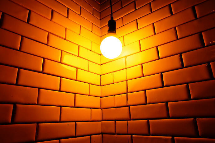 Lâmpada de luz amarela em um fundo de tijolos.