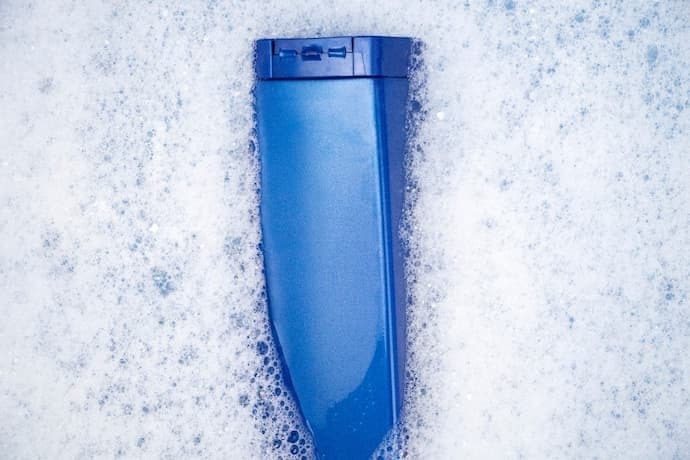 Uma lata de xampu azul flutua na água espumosa