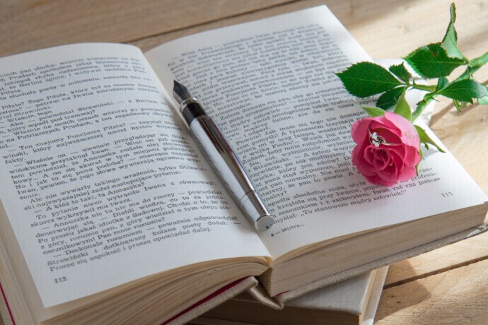 Livro aberto, flor e uma caneta sobre a mesa