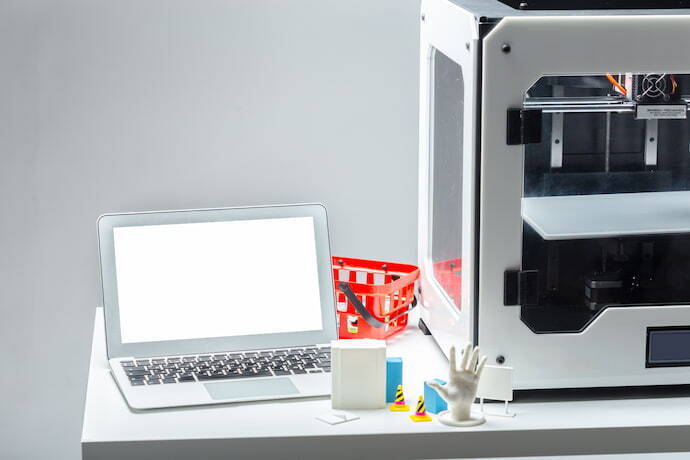 Computador ao lado de uma impressora 3D