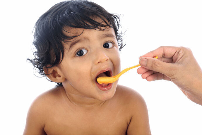 Criança sendo alimentada com colher dosadora 