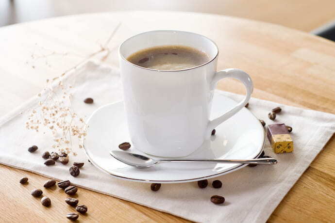 Xícara de café em cima de mesa com grãos em volta