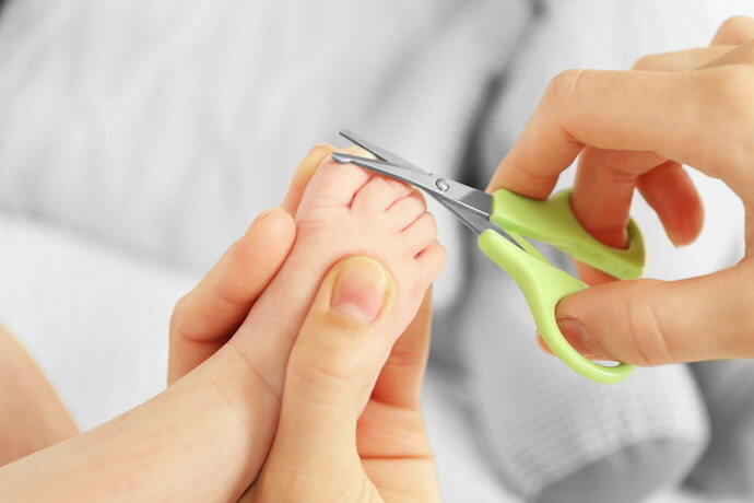 Pessoa cortando unha de bebê com tesoura anatômica 