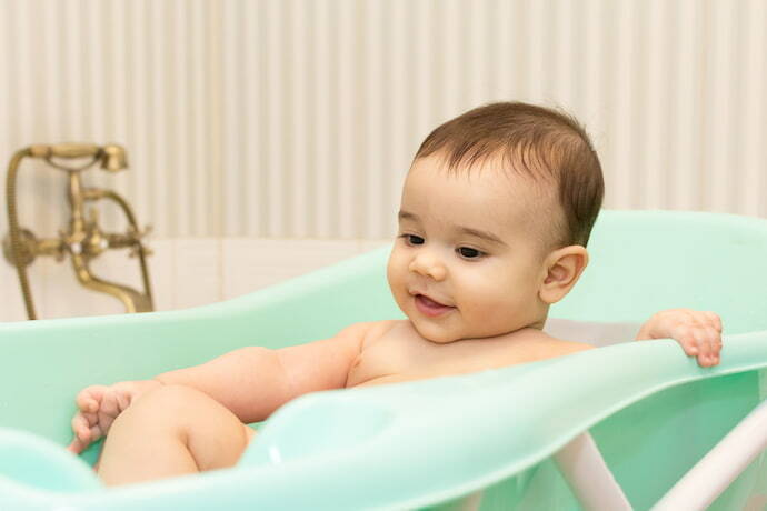 Bebê dentro de banheira com suporte