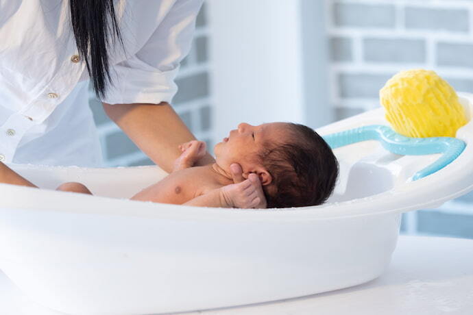 Mulher dando banho em bebê dentro da banheira