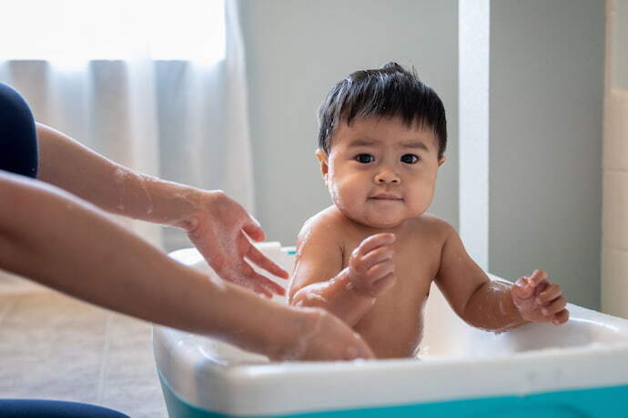 Mulher dando banho em bebê dentro da banheira