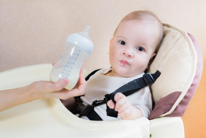 Bebê com cinto de segurança em cadeira de alimentação 
