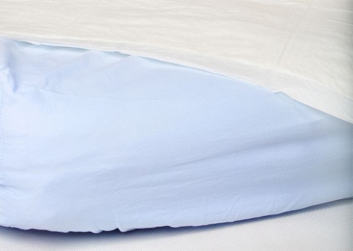 Colchão de berço impermeável azul coberto com manta branca.
