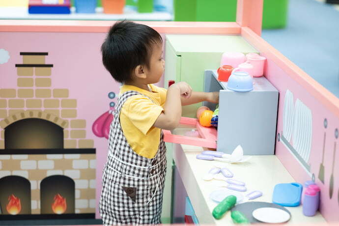 Criança brincando na cozinha de brinquedo