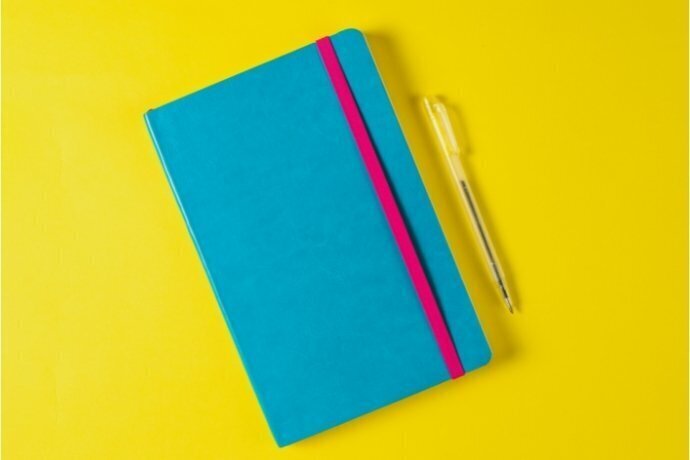 Caderno bullet journal azul fechado, com uma caneta ao lado