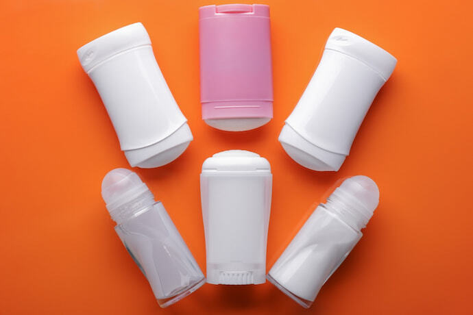 Frascos de desodorantes diferentes em fundo laranja