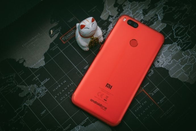 Parte de trás do celular Xiaomi vermelho em fundo com mapa mundi escuro.