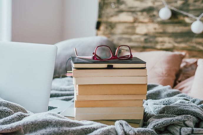Vários livros na cama e um óculos