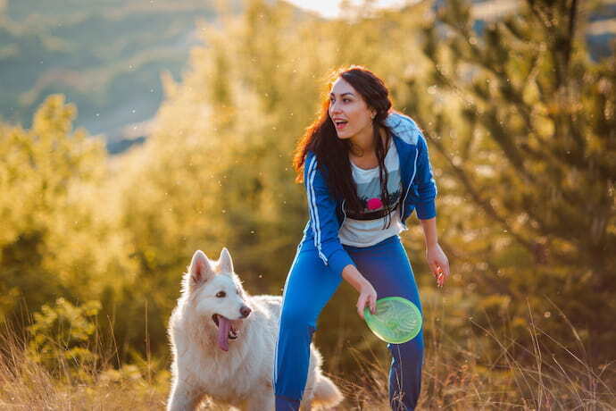 Mulher jogando frisbee para cachorro