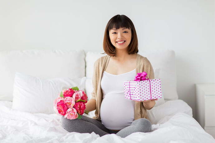 Mulher grávida sentada segurando presentes