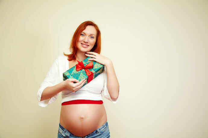 Mulher grávida segurando embalagem de presente