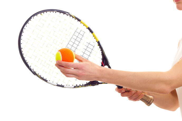 Pessoa posicionando bola na raquete de tênis