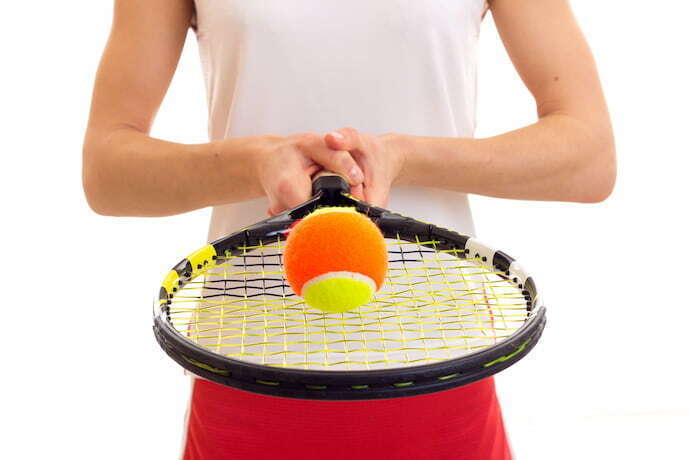 Pessoa segurando raquete de tênis e uma bola