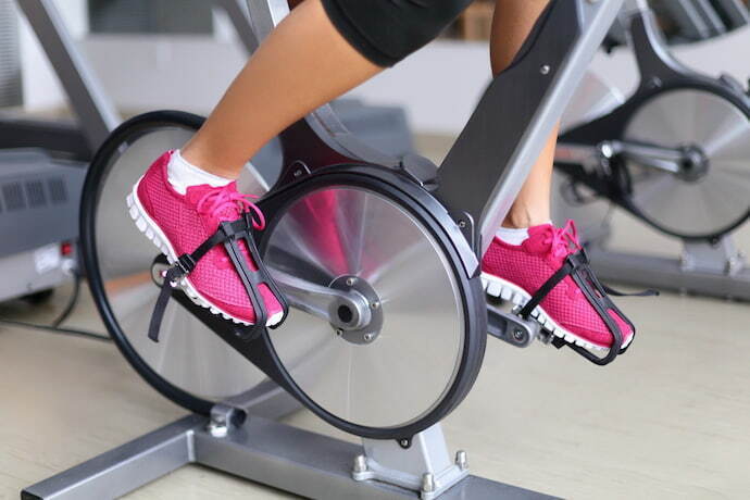 Mulher de sapatos rosas treinando em bicicleta de spinning