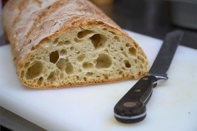 Faca de pão ao lado de pão cortado.
