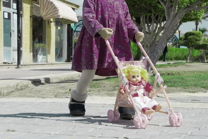 Menina com boneca em carrinho