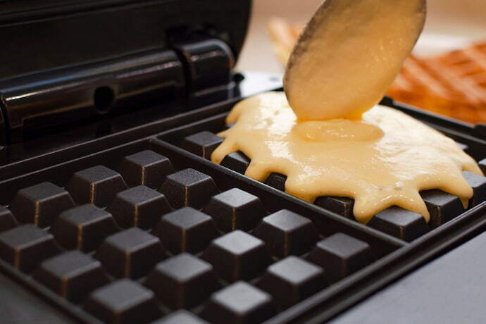 máquina de waffle bem perto e colher de pau