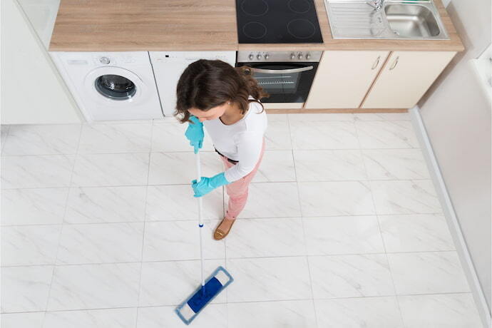 Mulher limpando o chão com vassoura mágica.
