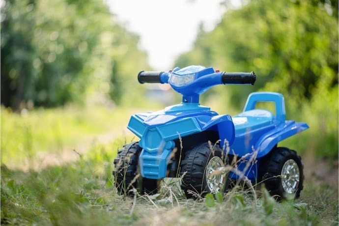 Carrinho com pedal azul para criança em grama.