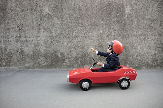 Criança andando em carrinho com pedal vermelho.