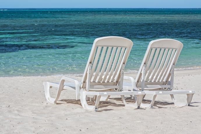 Duas cadeiras brancas na praia