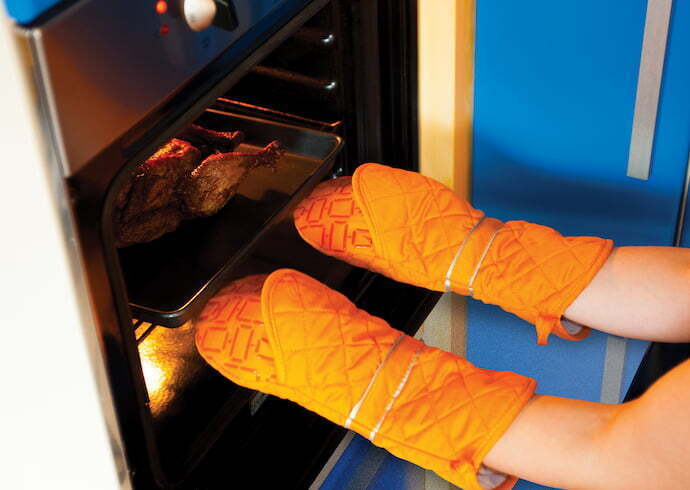 Pessoa usando Luva para cozinha para retirar comida do forno